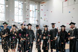 Joyful graduates celebrate commencement with confetti indoors, symbolizing achievement and diversity.